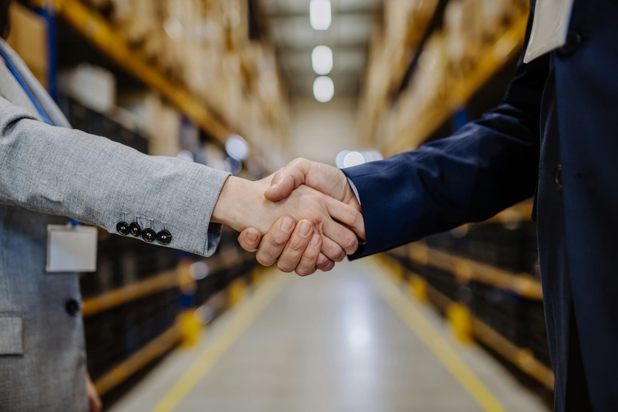 Close-up of managers shaking hands in warehouse.